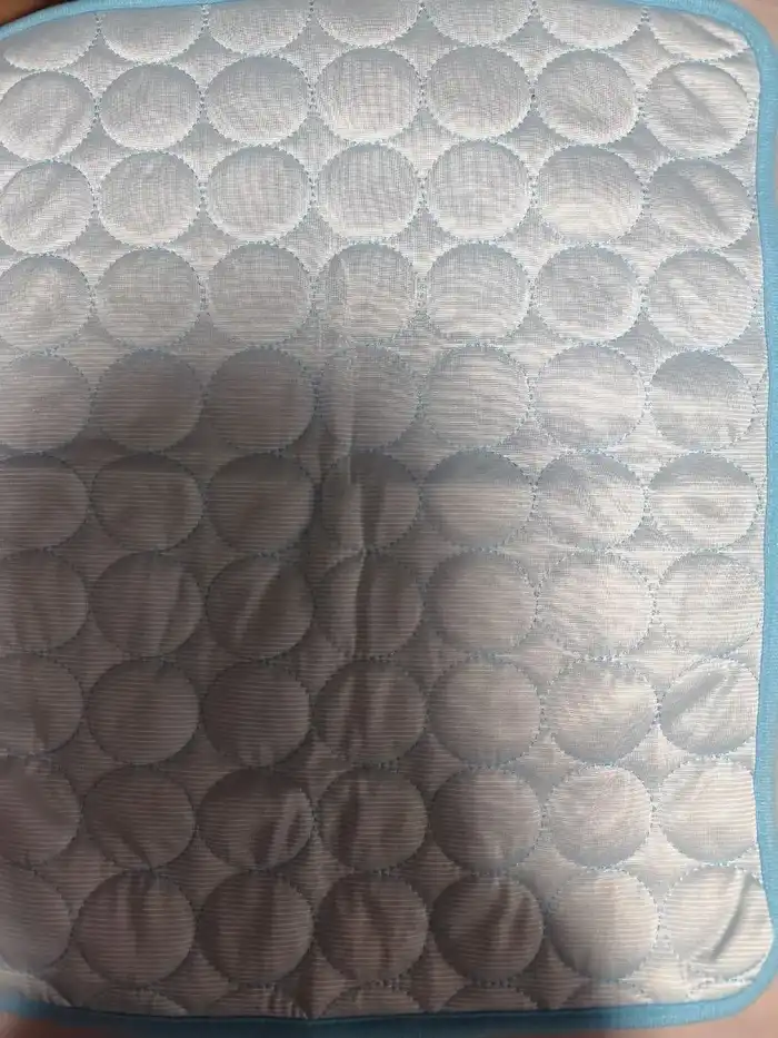 Tapis rafraîchissant bleu clair photographié de près par une acheteuse, surface matelassée visible