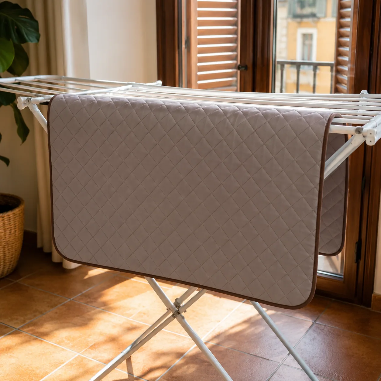Tapis rafraîchissant Frimouf gris étendu sur un séchoir à linge devant une fenêtre ouverte